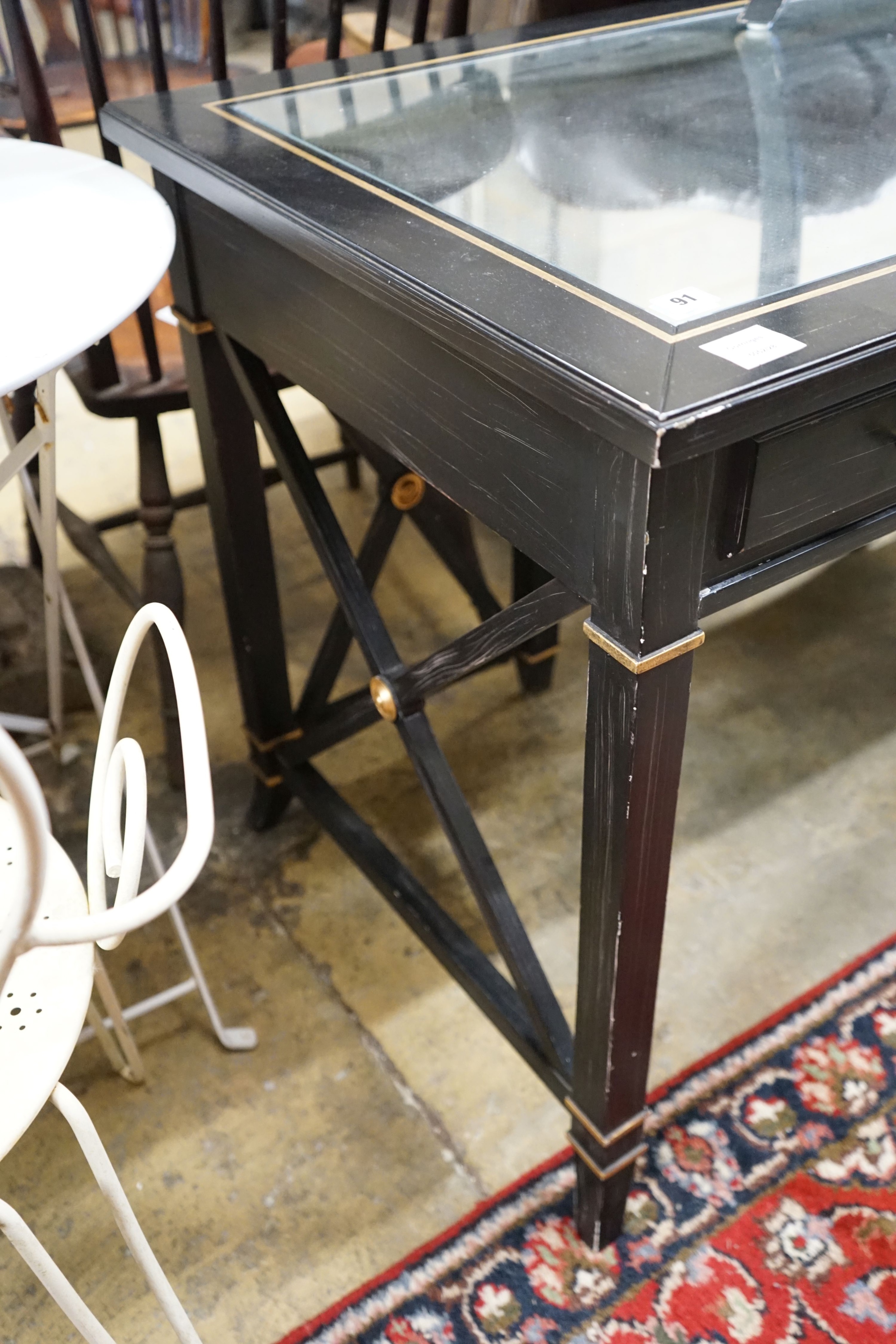 A painted mirrored three drawer ebonised writing table, length 140cm, depth 64cm, height 76cm together with a matching tub framed elbow chair